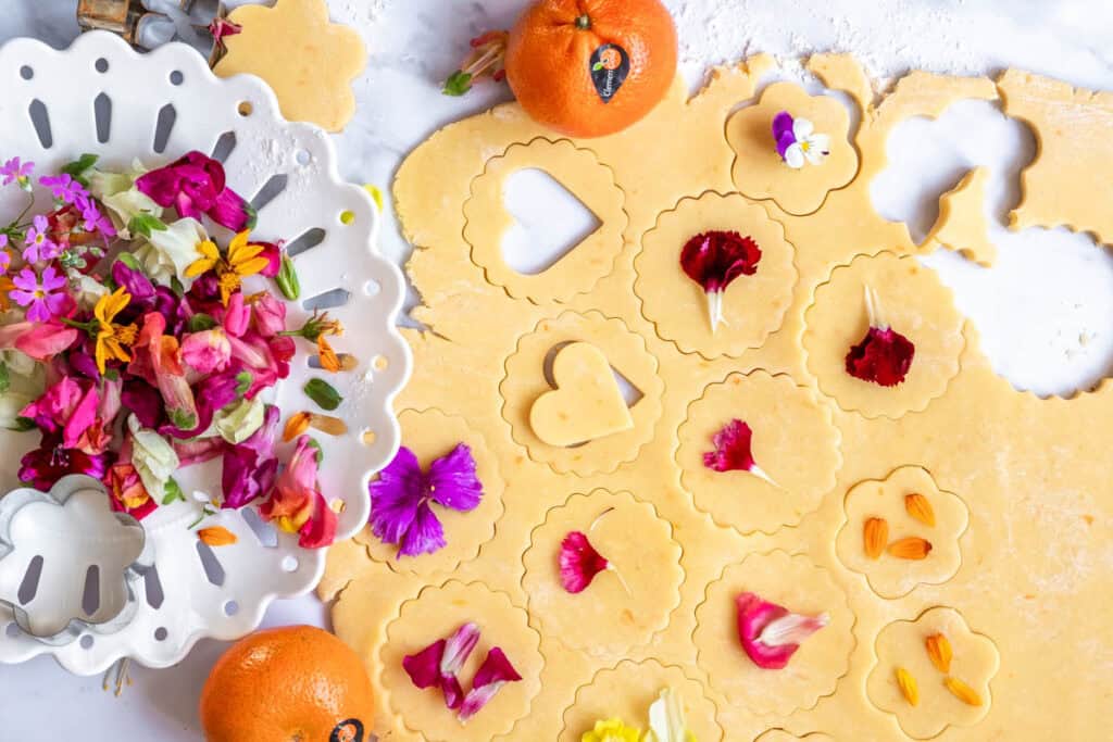 Shortbread Style Jam Sandwich Cookies shown being made. Dough being rolled out next to fresh flowers