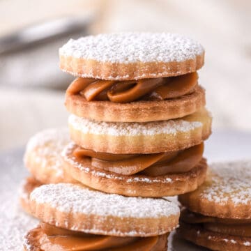 Dulce de Leche Cookies stacked on a plate and dusted with icing sugar