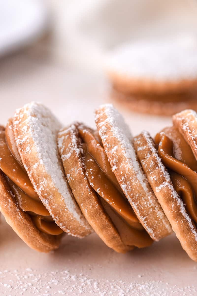 Dulce de Leche Cookies shown in a row on a light pink counter.