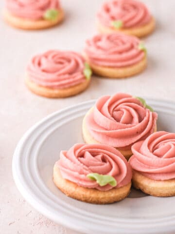 Buttercream cookies shown on a white cake plate on a kitchen counter