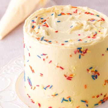 Mini Birthday Cake covered in sprinkles shown on a white cake plate.