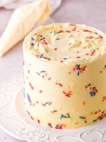 Mini Birthday Cake covered in sprinkles shown on a white cake plate.