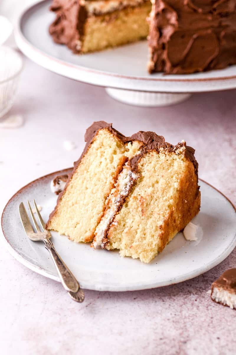 A slice of Bounty Cake on a white plate next to a fork. 